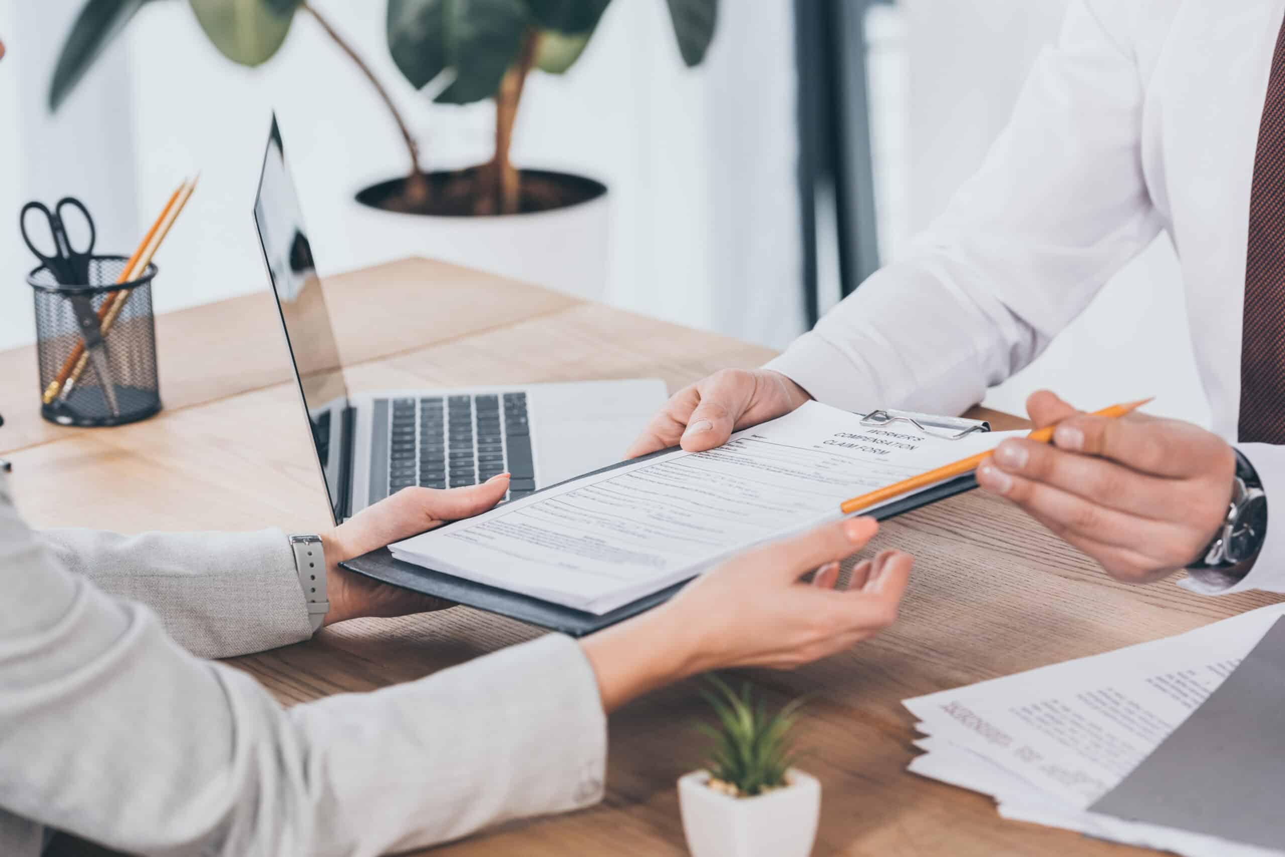 cropped view of businessman giving compensation claim form to wo