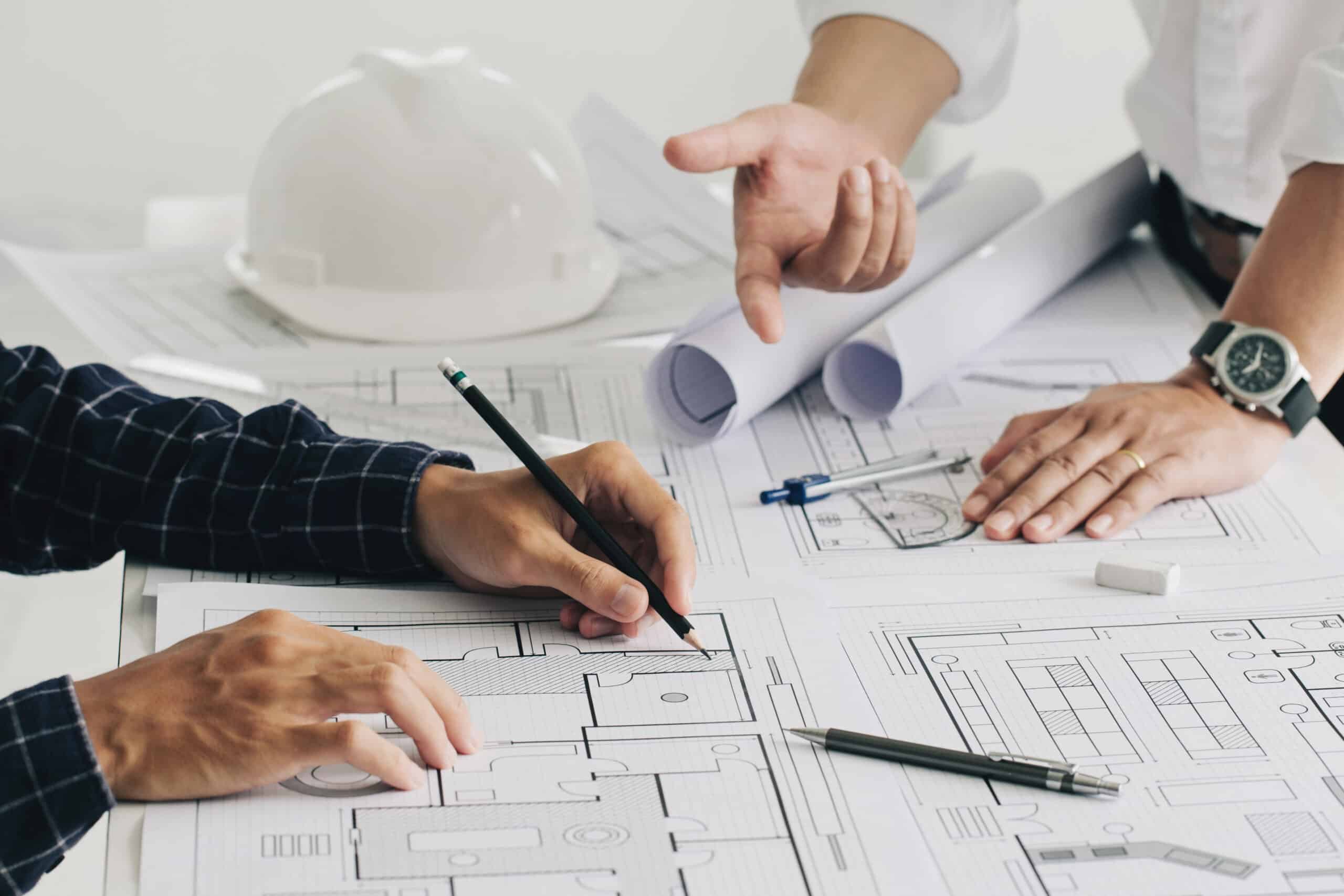 Two business man construction site engineers. working drawing on blueprint and discussing the floor plans over blueprint architectural plans at table in a modern office. construction concept